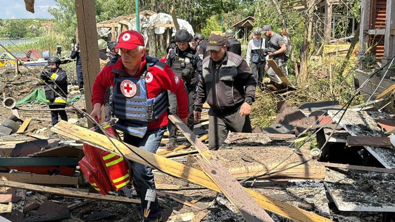 Volontärer och frivilliga tar sig förbi ruiner och bråte från hus som förstörts i strider.