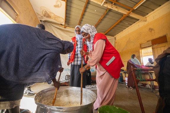 Sudanesiska kvinnor rör om i stor gryta