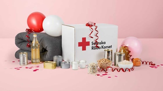 Ett matpaket och ullfilt från Röda Korset täckt i serpentiner, ballonger och konfetti.