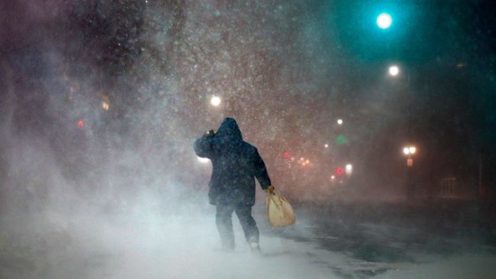 Man är ute och går i en snöstorm