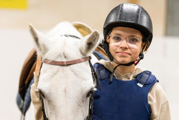 Glad Rebecca står i klänning vid vattenpump